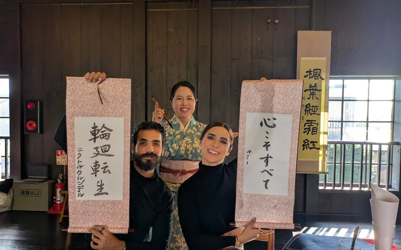 Toshu in kimono with two guests, each holding their finished hanging scroll