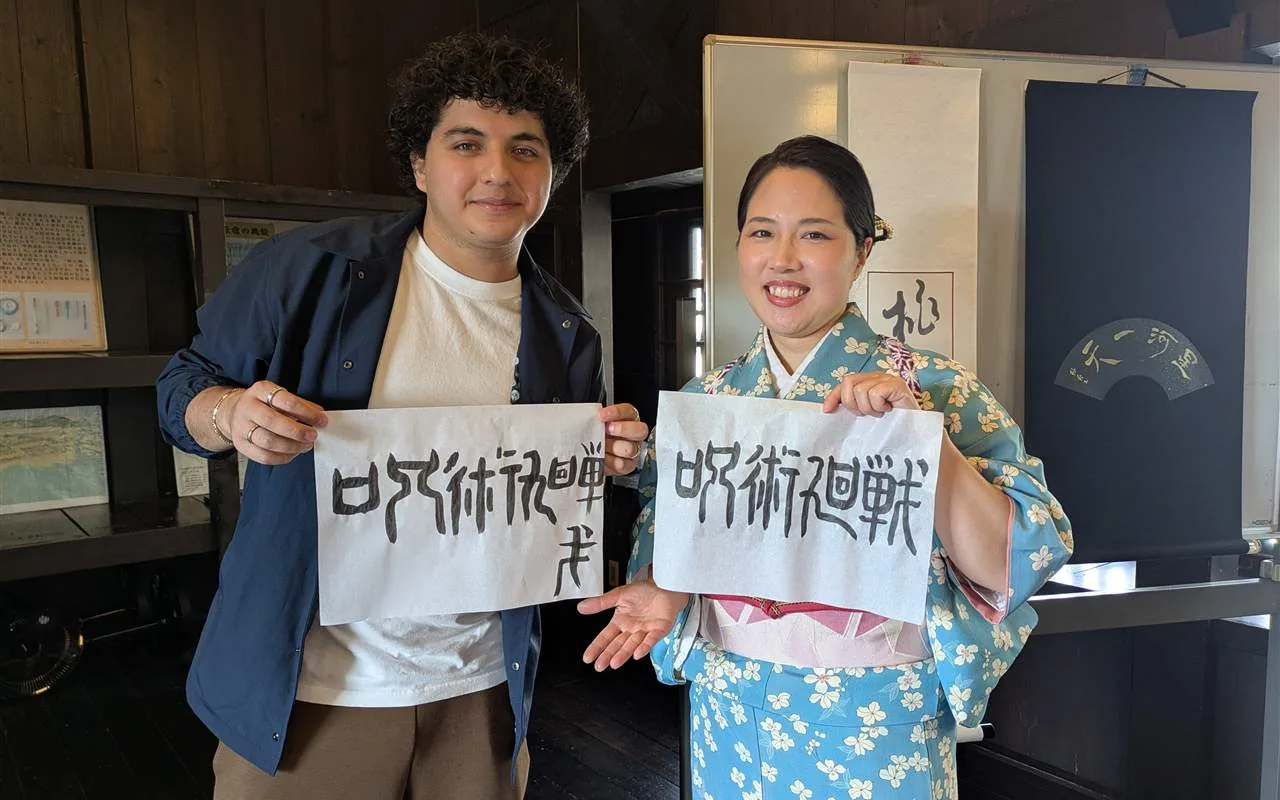 A guest and Toshu comparing their finished calligraphy works