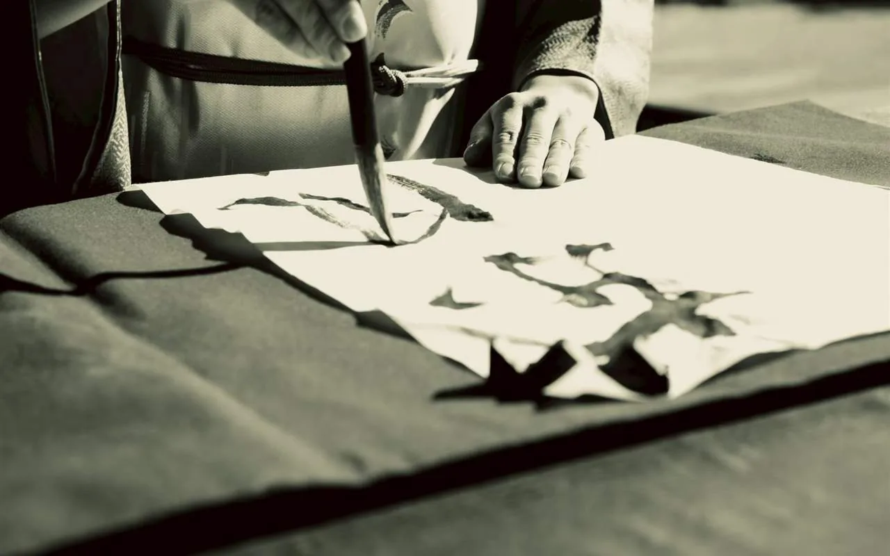 Black and white close-up of hands writing calligraphy